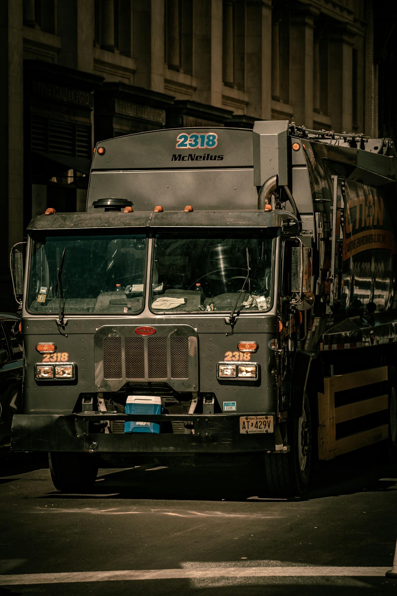 A garbage truck navigates the bustling streets of New York City in an urban setting.