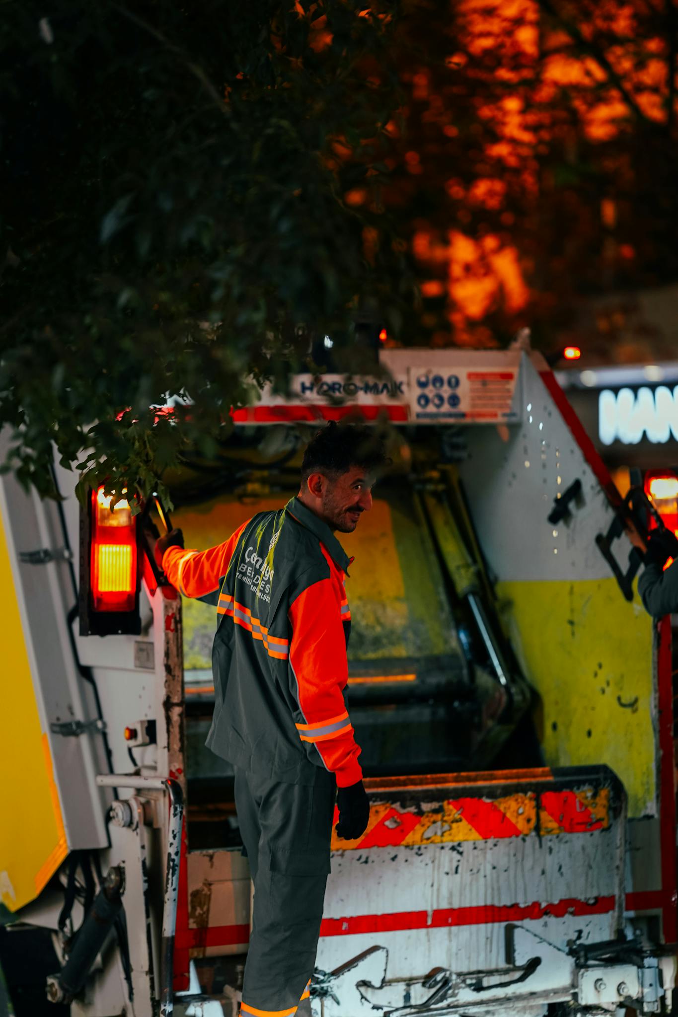 Urban garbage collector in reflective gear managing waste in Ankara, Türkiye at night.
